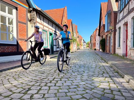 Zwei Radfahrerinnen fahren an Fachwerkhäusern in Nienburger vorbei